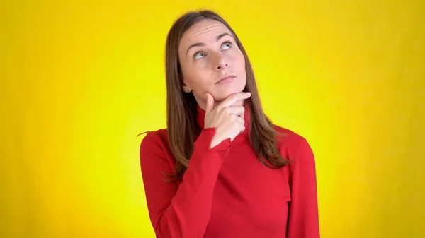 Jeune femme isolée sur fond jaune en studio. Les gens émotions sincères, concept de style de vie. Regarde la caméra, pense, rayures au temple vient avec des idées — Photo