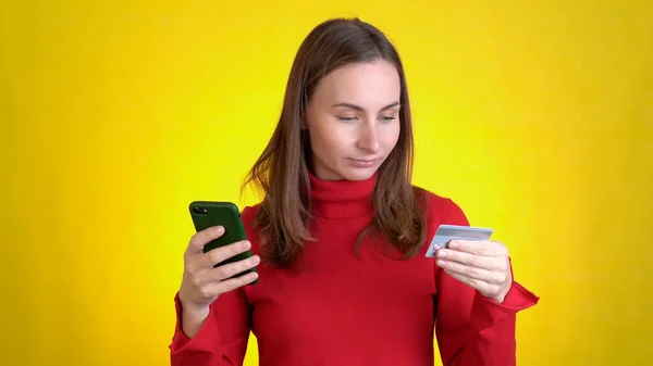 Mujer feliz que usa el teléfono celular de tarjeta bancaria de crédito de mano acaba de descubrir grandes noticias de ganancias aisladas en el estudio de fondo amarillo Concepto de estilo de vida de la gente — Foto de Stock