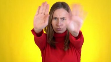 Sarı arka plan stüdyosunda yalnız poz veren çılgın bir kadın. Kulakları parmaklarıyla kapat, gözleri kapat ve çığlık at.