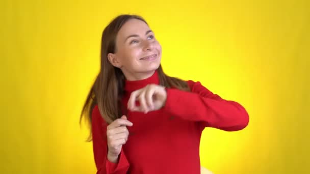 Junge Frau posiert isoliert auf gelbem Hintergrund. Menschen Lifestyle-Konzept. Tanzen albern herum und haben Spaß mit ausdrucksstark gestikulierenden Händen — Stockvideo