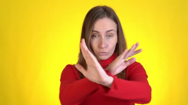 Displeased worried young woman posing isolated on yellow background studio. Say no showing stop gesture with palm crossed hands — Stock Video