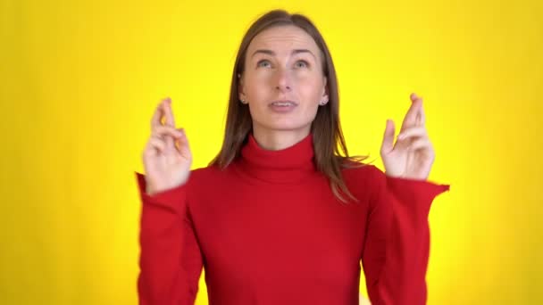 Jeune femme regarder caméra bits lèvres mains pliées dans la prière mendier sur quelque chose de bon garder les doigts croisés faire souhait isolé sur fond jaune en studio. — Video