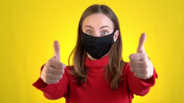 Mujer aislada en estudio de fondo amarillo. Estilo de vida saludable enfermedad enferma tratamiento frío concepto de temporada. Señalando los dedos índice en la mascarilla que muestra los pulgares hacia arriba — Vídeo de stock