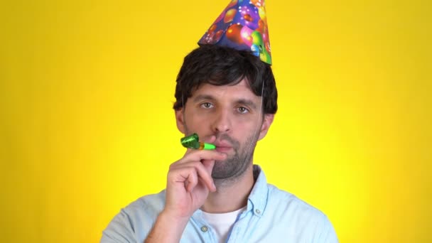 パイプの誕生日の帽子の基本的な悲しい動揺深刻な男は黄色の背景スタジオに隔離されたパーティーの日を祝う。人々のライフスタイルの休日の新年のコンセプト — ストック動画