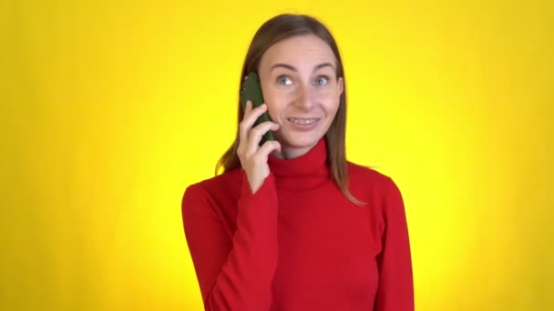 Lächelnde Frau, die mit dem Handy spricht und angenehme Gespräche führt, isoliert auf gelbem Hintergrund im Studio. Lebensstil-Konzept der Menschen — Stockvideo