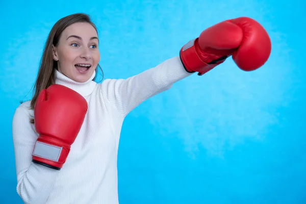 Image of a screaming strong young woman boxer posing isolated over blue background wall wearing boxing gloves. — Stock Photo, Image