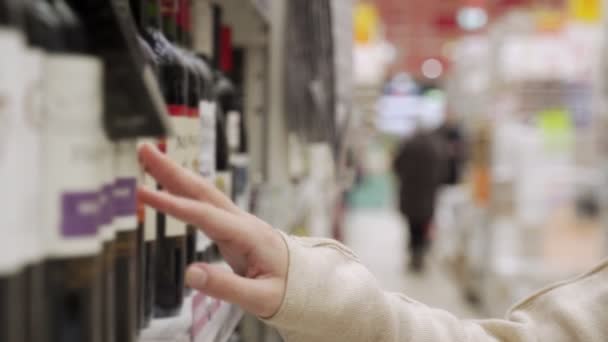 Femme sélectionnant bouteille de vin au supermarché — Video