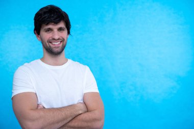 Mavi arka planda, gündelik izole edilmiş genç yakışıklı bir adamın portresi.