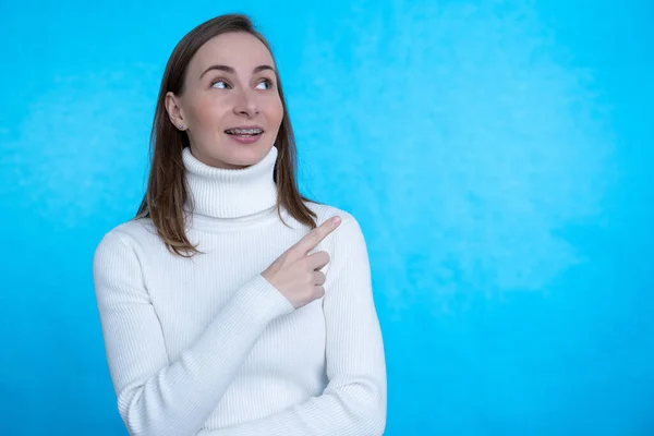 Foto de mujer en estado de ánimo excitado que indica el dedo al espacio vacío aislado fondo de color azul — Foto de Stock