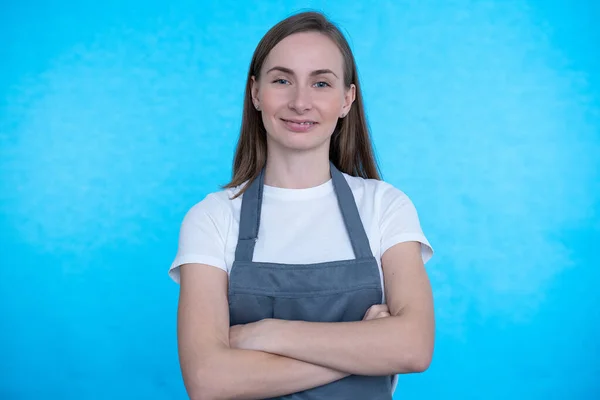 Молодая улыбающаяся шеф-повар в фартуке на синем фоне — стоковое фото