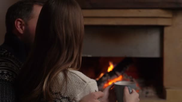 Pareja romántica joven sentada frente a la chimenea en casa — Vídeo de stock