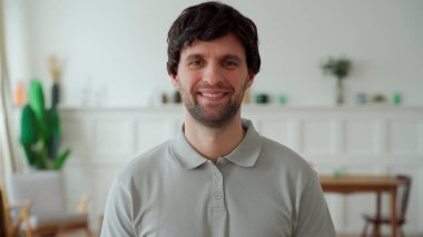 Gri gömlekli mutlu bir adamın portresi kameraya bakıyor ve gülümsüyor.