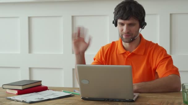 Sonriente operador de centro de llamadas masculino haciendo su trabajo con un auricular. — Vídeo de stock