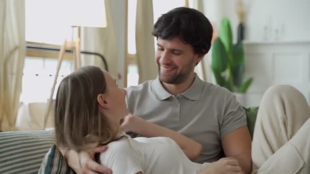 Unga par i kärlek kramar på soffan i vardagsrummet, njuter av att tillbringa tid tillsammans — Stockvideo