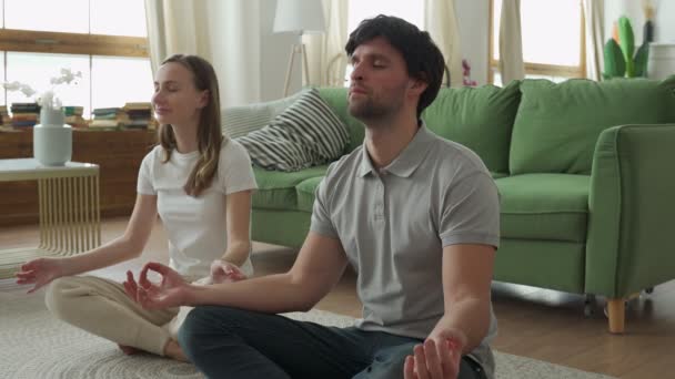 Giovane coppia sta facendo allenamento fitness a casa. Fare yoga insieme. Stile di vita sano concetto. — Video Stock