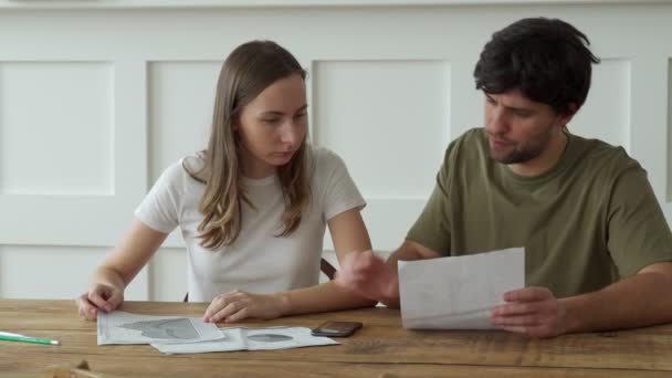 Наголошена молода пара розраховує щомісячні витрати на житло, оплату рахунків за кредитними картками . — стокове відео