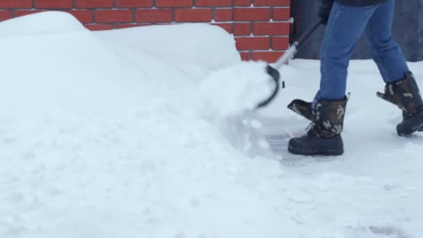 Genç adam banliyödeki evin yakınındaki karları temizler. — Stok video