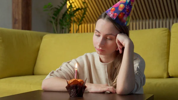 Portrait d'une fille triste avec un morceau de gâteau avec une bougie, la fille souffle la bougie — Photo