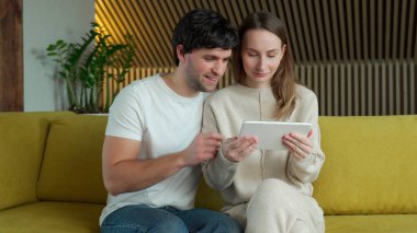 Genç bir çift evdeki kanepede oturup internetten medya içeriğini izliyor.