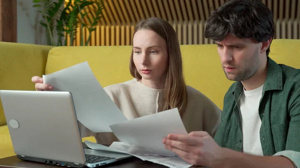 Jong stel zit op de gele bank thuis en het beheer van het budget met behulp van laptop — Stockfoto