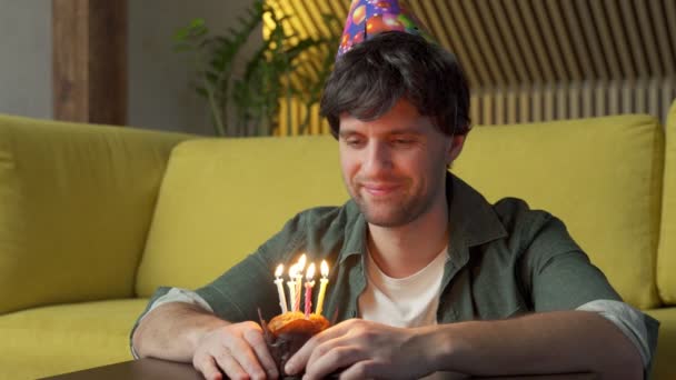 Joven celebrando cumpleaños sopla velas en el pastel. — Vídeo de stock