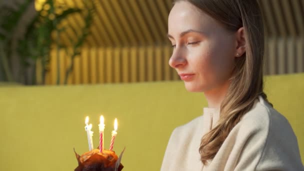 La donna esprime un desiderio, spegne le candele su una torta di compleanno e ride — Video Stock