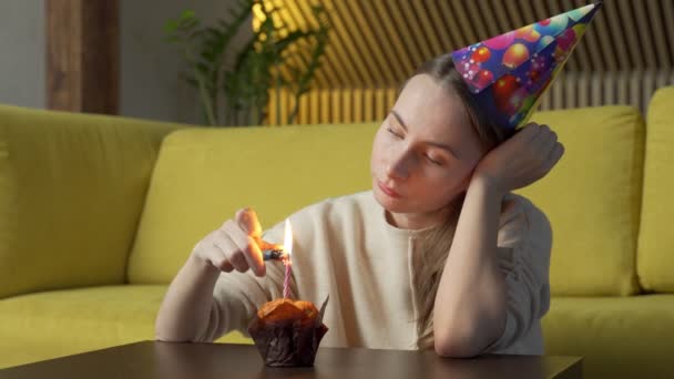 Retrato de uma menina triste com um pedaço de bolo com uma vela, a menina apaga a vela — Vídeo de Stock