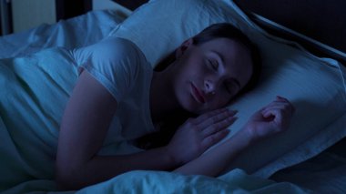 Genç bayan geceleri evdeki bir yatakta rahatça uyuyor. Uyku zamanı.