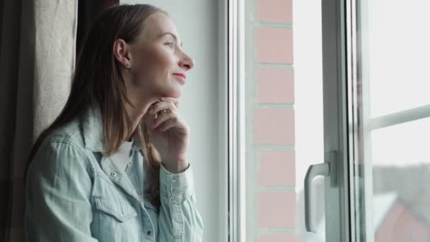 Avslappnad omtänksam kvinna hemma sitter vid fönstret — Stockvideo