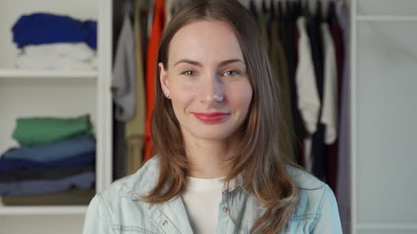 Portrét ženy, která stojí na pozadí velkého šatníku šatník se stylovým oblečením a předměty pro domácnost — Stock video