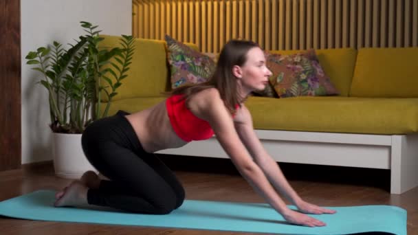 Giovane donna pratica yoga su un tappeto a casa la sera — Video Stock