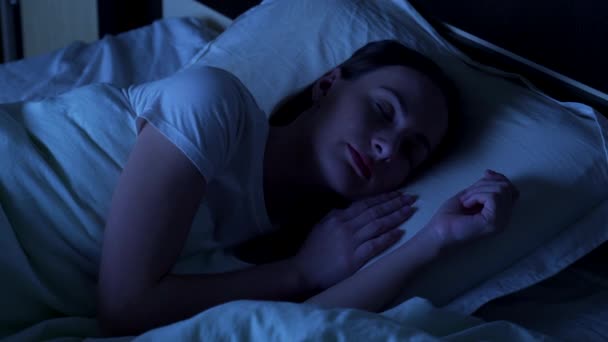 Νεαρή γυναίκα κοιμάται άνετα το βράδυ σε ένα κρεβάτι στο σπίτι. Χρόνος ύπνου — Αρχείο Βίντεο