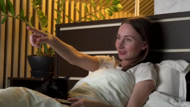 女性は夜遅くにテレビシリーズを見てベッドの上に横たわっている — ストック動画