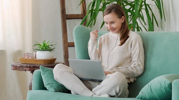 Happy woman excited and glad of success with laptop on chair