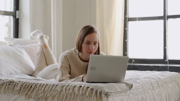 令人惊讶的年轻女性看着她的笔记本电脑在网上赢了看躺在床上的内容 — 图库视频影像