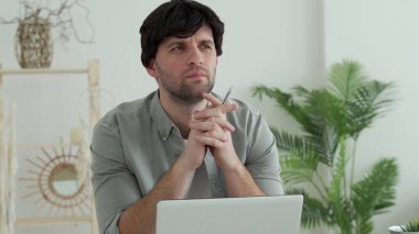 Genç adam bilgisayarın önünde oturuyor ve ilham verici arama sorunu çözümü fikirleri düşünüyor.