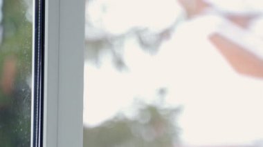 Adamın eli oturma odasındaki pencereyi kapatıyor.