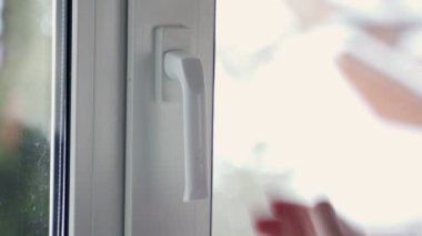 Kadın perdeleri ve evdeki beyaz plastik pencereyi açtı.