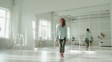 Mutlu genç bir kadın odaya atlıyor, başarıyı kutluyor.