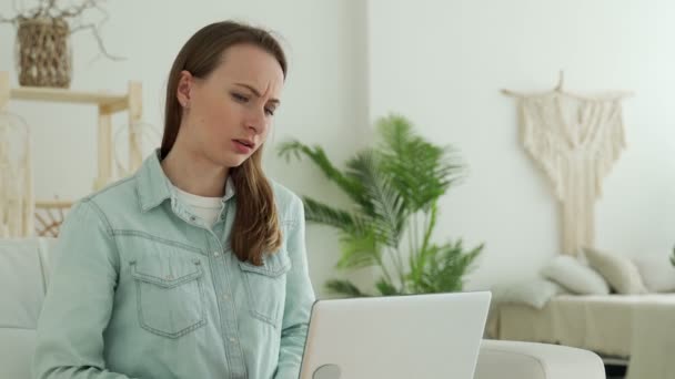 Ung kvinna får mycket dåliga nyheter på sin bärbara datorskärm, upprörd och frustrerad över misslyckande — Stockvideo
