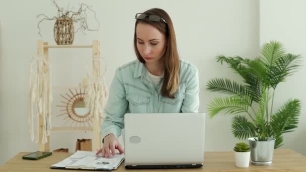 Mulher morena feliz trabalhando em um laptop em casa. — Vídeo de Stock