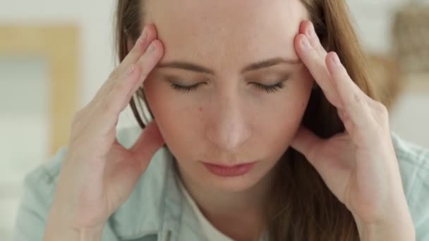 Крупним планом сумна втомлена жінка торкається голови з головним болем або депресією — стокове відео