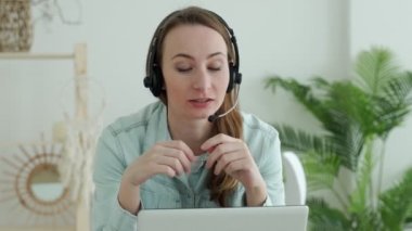 Esmer kadın dizüstü bilgisayar konuşmalarında kulaklık takıyor. İnternet öğretmeniyle çalışıyor, evden çalışıyor..