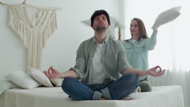 Hombre meditando sentado en el sofá mientras activa mujer enérgica saltando jugando — Vídeos de Stock