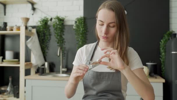 Mooie jonge vrouw in een schort eten chocolade in de keuken thuis — Stockvideo