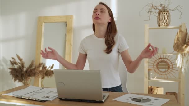 Junge Frau mit geschlossenen Augen meditiert gespreizte Hände in Yoga-Pose sitzt nach der Arbeit am Schreibtisch mit Laptop — Stockvideo