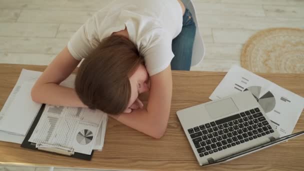 若いです疲れている女性寝ています彼女のオフィスデスク近くに彼女のラップトップ — ストック動画