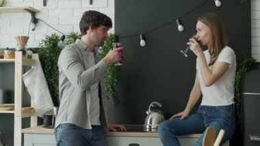 Genç çift evde mutfakta konuşuyor. Çift kırmızı şarap içiyor. 