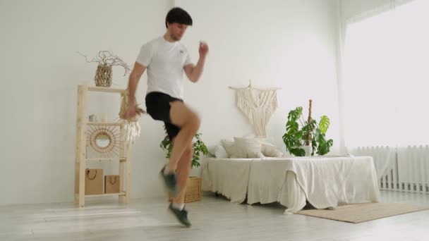 Sportlicher Mann läuft auf der Stelle, trainiert zu Hause, macht Ausdauertraining in Sportkleidung. — Stockvideo