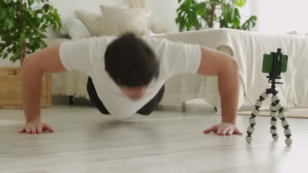 Homme fitness blogueur enregistre des clips à la maison, fait push-ups. Le jeune homme va faire du sport à la maison. — Video